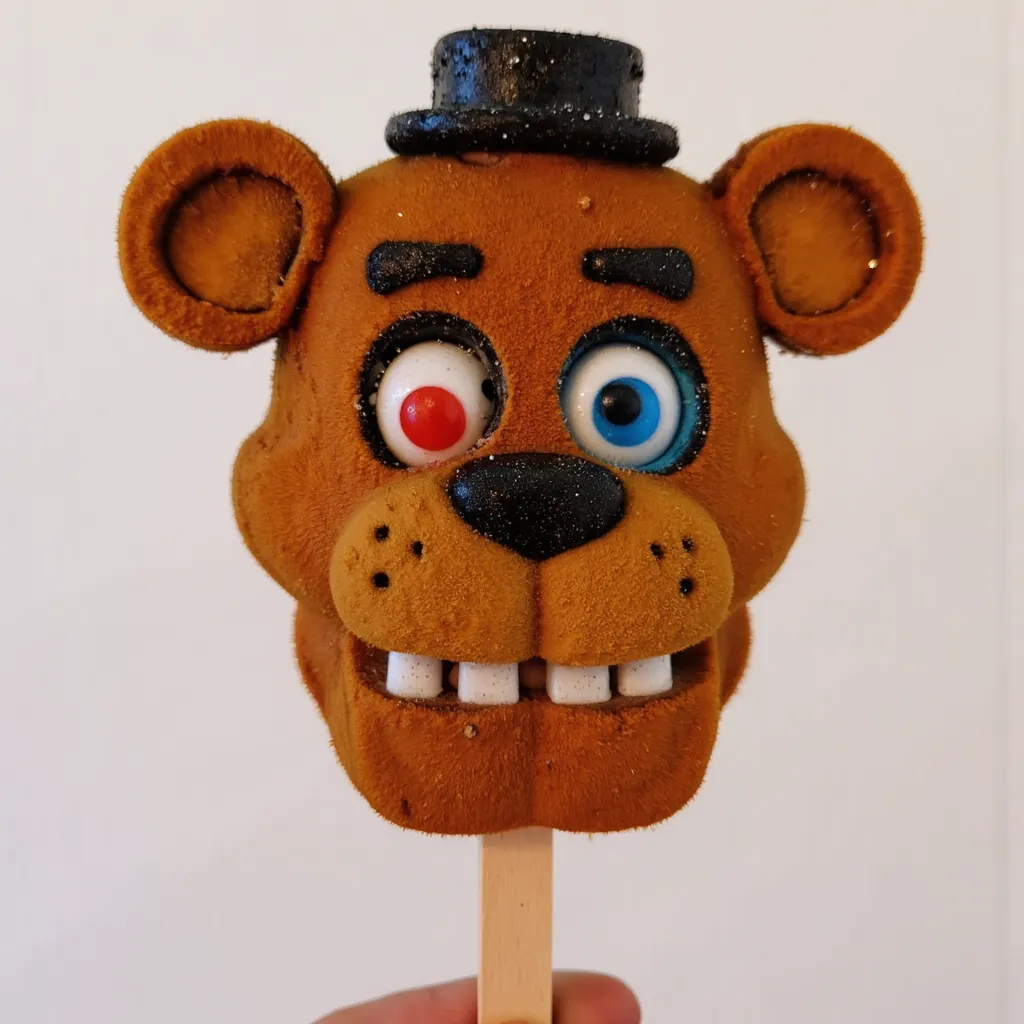 character popsicle of Freddy Fazbear, head, on a stick, gumball eyes