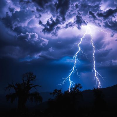 A powerful, ethereal lightning bolt arcing through a turbulent stormy sky, crackling with intense energy, its jagged edges illuminated by vibrant shades of electric blue and vivid white. Beneath, a dramatic landscape of charred trees and scorched earth, remnants of a recent wildfire casting dark silhouettes against the flashes of light. The atmosphere is charged with tension, a sense of impending danger contrasted by the beauty of nature's fury. The scene is enhanced by swirling dark gray storm clouds, interspersed with hues of deep purple, as the lightning cuts through, creating a hyper-realistic portrayal of nature's power and resilience.